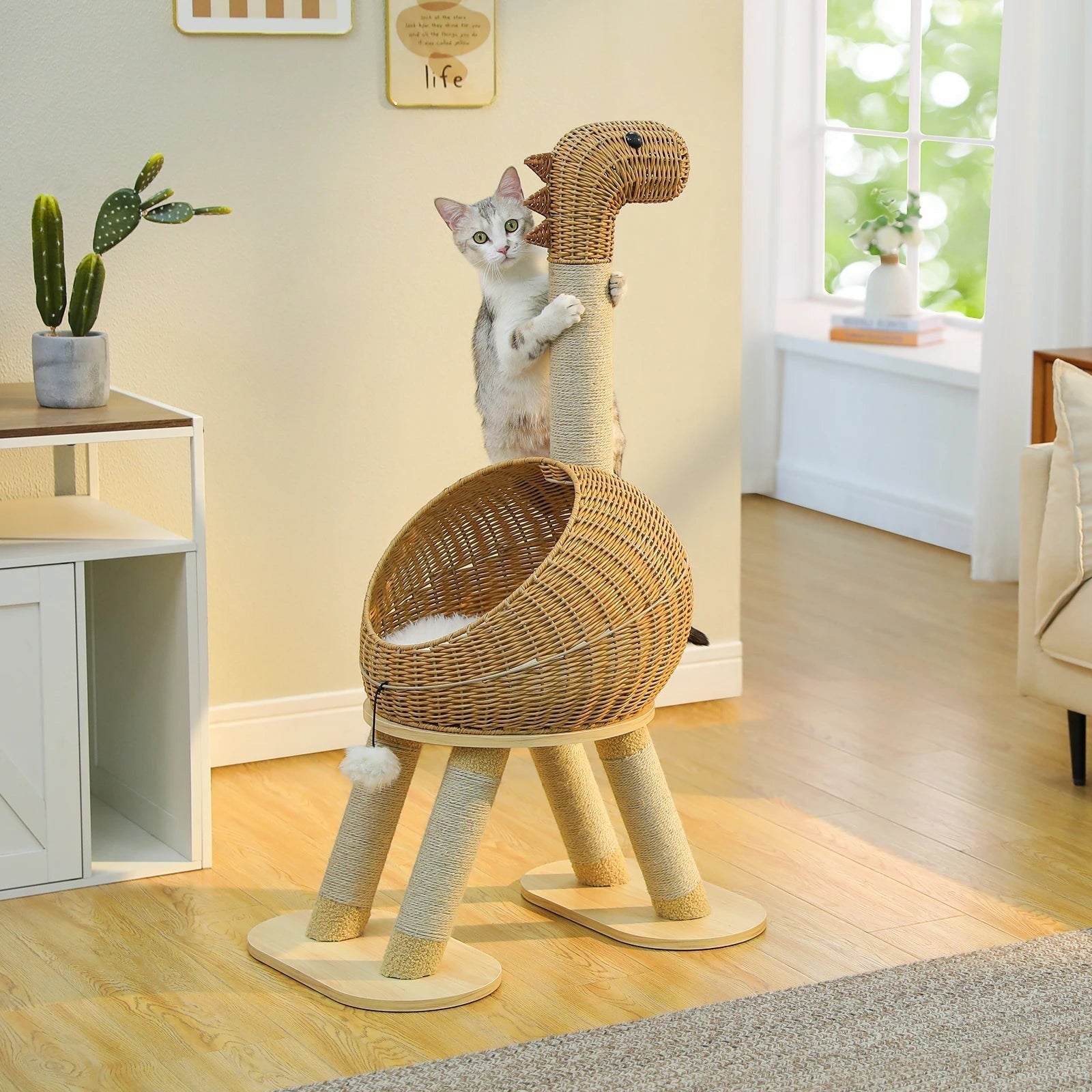 Tailwag Factory dinosaur-shaped cat tree with sisal-wrapped legs and a rattan lounge bed, featuring a cat playing.