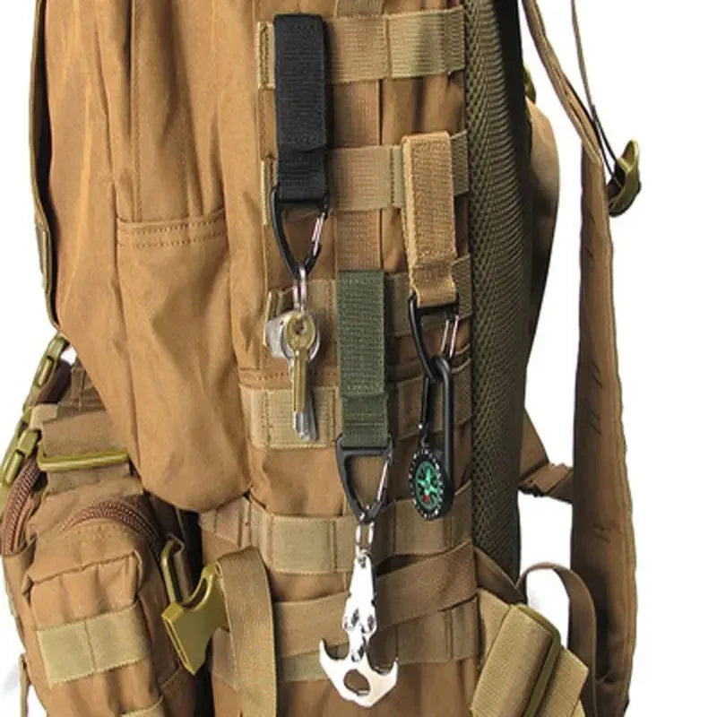 Tailwag Factory tactical MOLLE key hook clips attached to a tan backpack, holding keys and tools on nylon webbing.